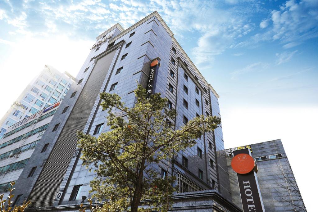 ein hohes Gebäude mit einem Baum davor in der Unterkunft Bucheon SR Hotel in Bucheon