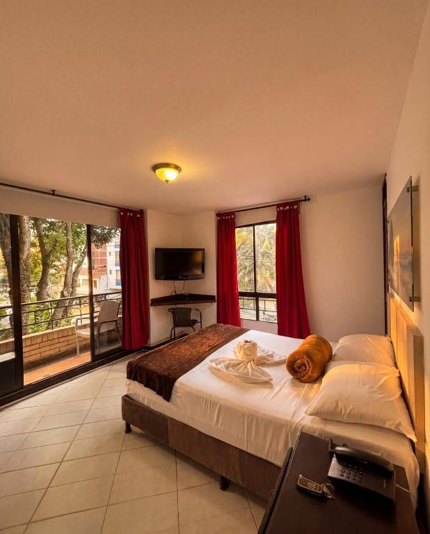 a bedroom with a large bed with red curtains at Hotel Estadio Real in Medellín