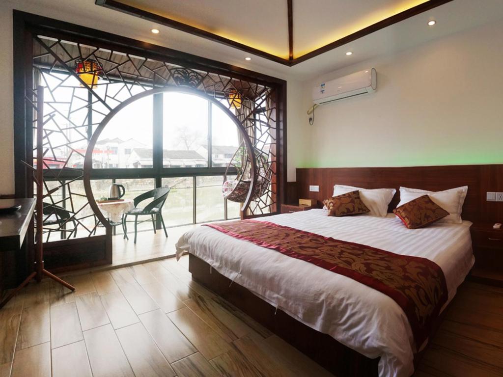 um quarto com uma cama grande e uma janela grande em Wuzhen On Memory Inn em Tongxiang