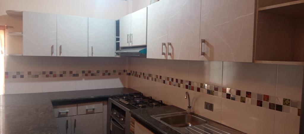 a kitchen with white cabinets and a sink at Los Ceibos Hostal in Montecristi