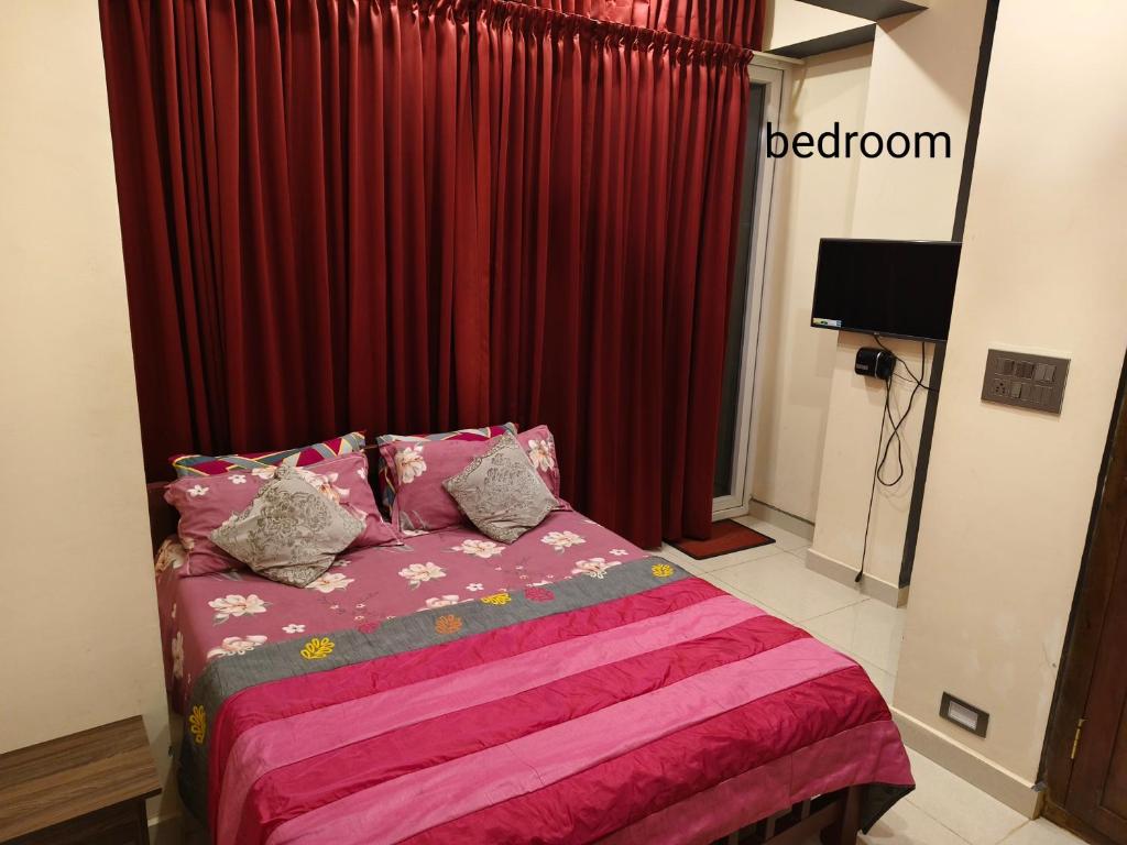 a bedroom with a bed with red curtains at The single room for two in Madikeri