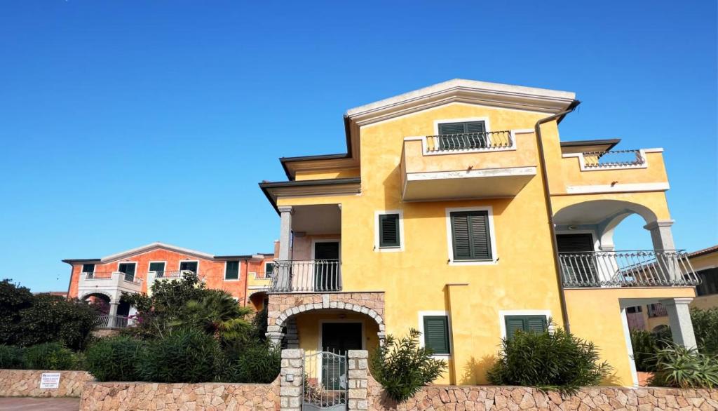 a yellow house with a blue sky in the background at Appartamento Eli in Valledoria