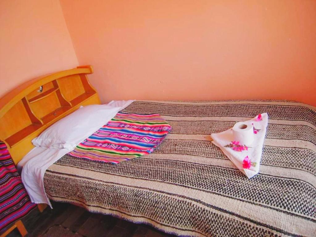 a bed with blankets and pillows on top of it at casa inti lodge in Isla Amantani