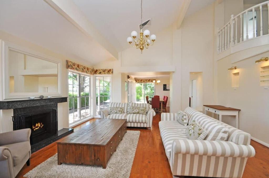 a living room with white furniture and a fireplace at Beggars Bridge Vineyard Homestead with pool and tennis in Rothbury