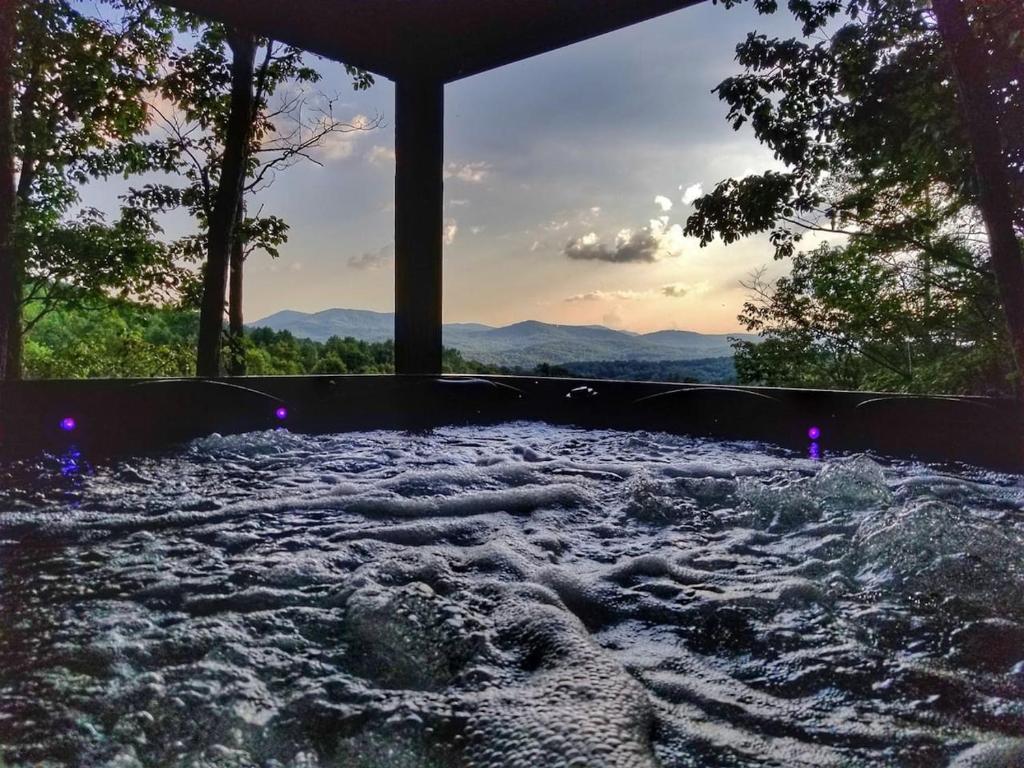 a hot tub filled with water with mountains in the background at Trail`s End-Hot tub-wifi,-pets ok-Pool Table-Fireplace-Screened Porch-Activities in Mashburn Mill