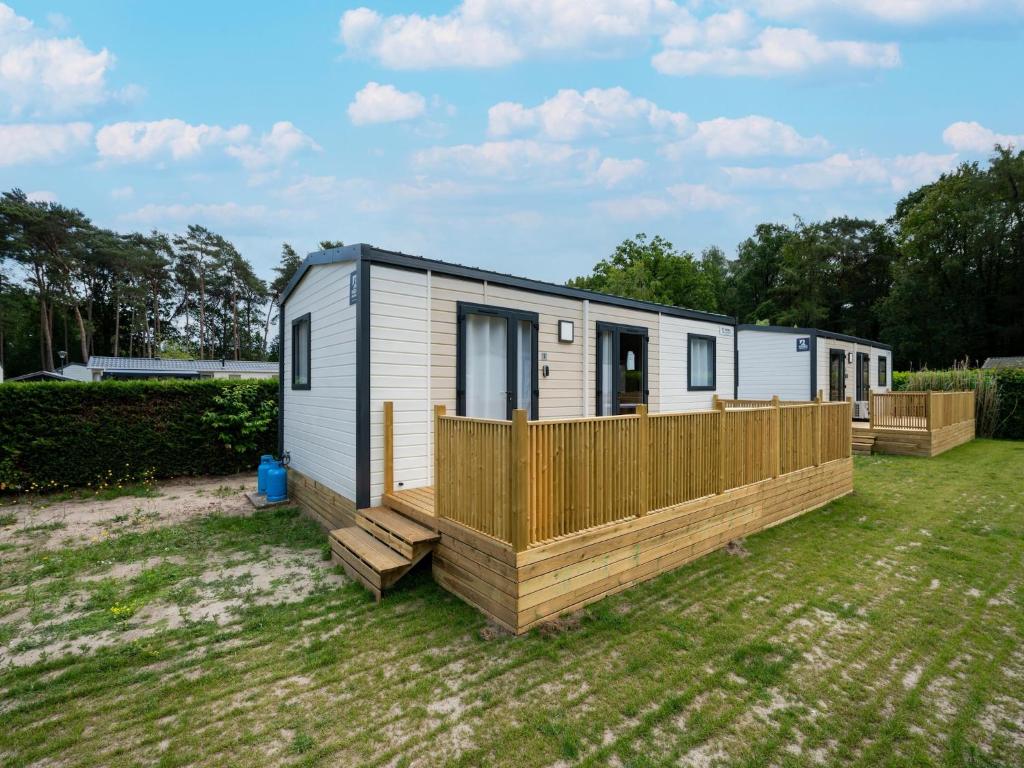 a tiny house with a wooden deck in a yard at Cozy Caravan Escape for 6 in Vierhuizen