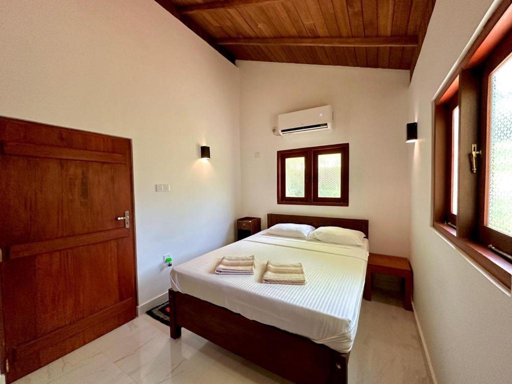 a bedroom with a bed with white sheets and a wooden door at Body,Mind & Soul in Bentota