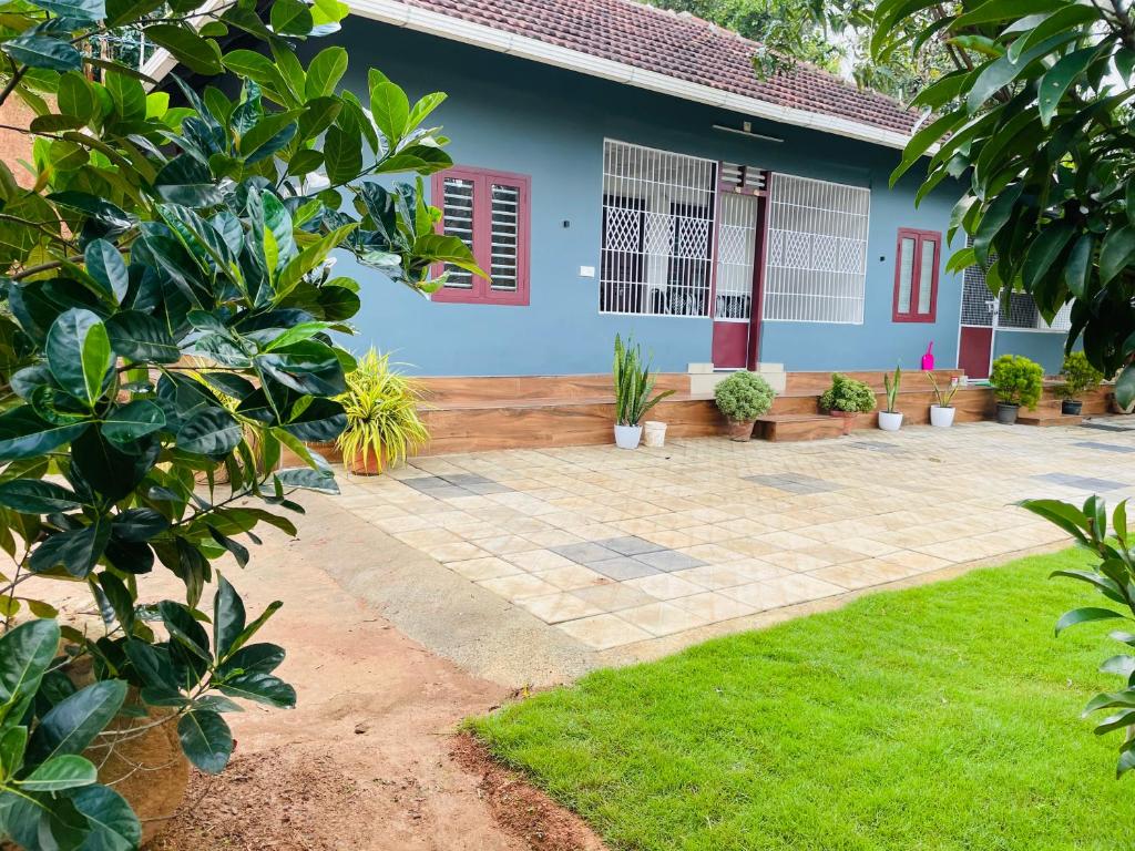 a blue house with plants in front of it at CHRIS COZY FARM cottage in Wayanad
