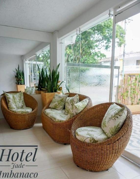 a living room with two wicker chairs and a large window at Hotel Jade Imbanaco in Cali