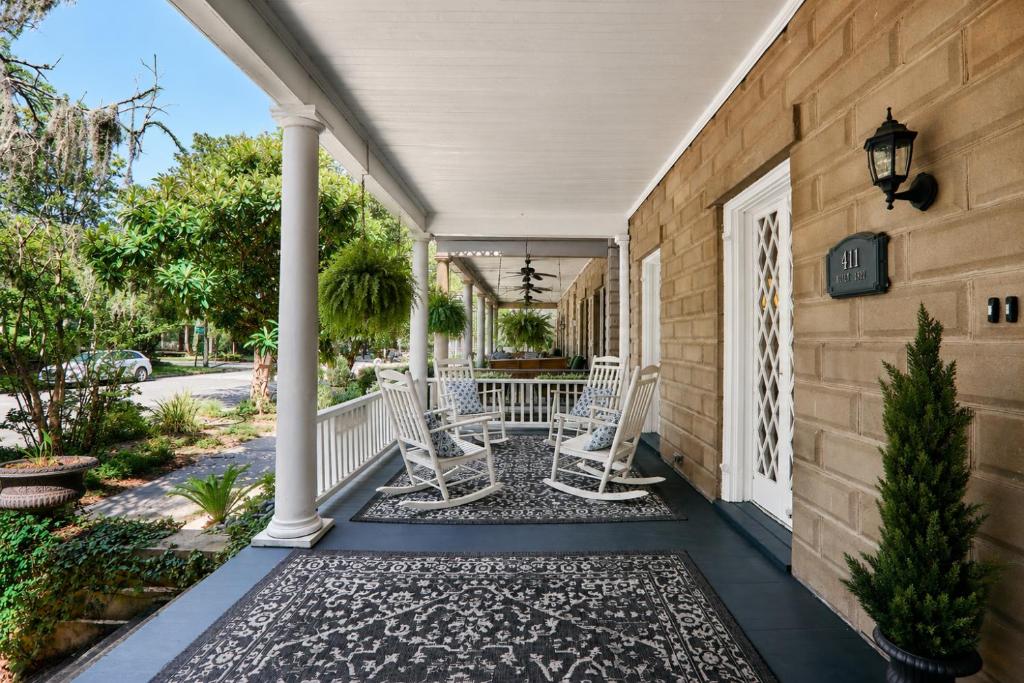 a porch with white chairs and a table at Downtown Savannah Oasis in Savannah