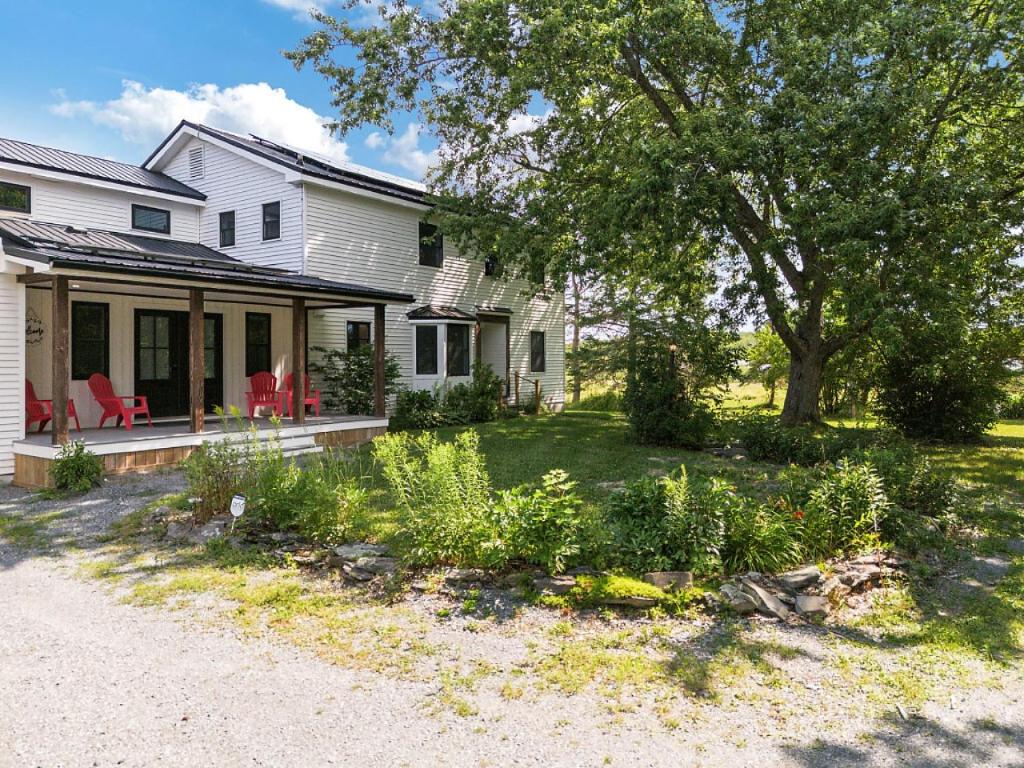 a house with a porch and a yard with plants at Spacious Colonial Large Groups Fire Pit in Brewer