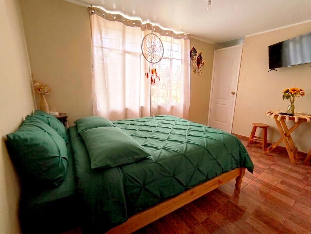 a bedroom with a green bed and a window at La Terraza in Oxapampa