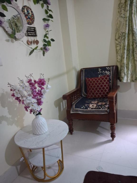 a room with a chair and a table with a vase of flowers at Paras home in Deoghar
