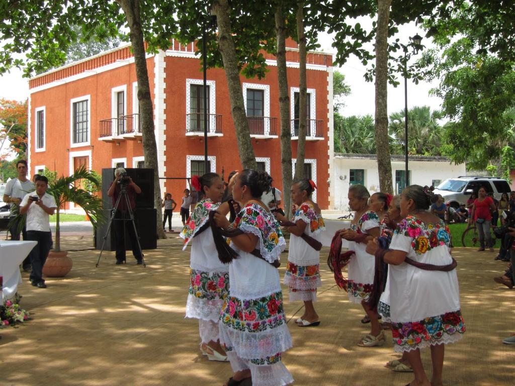 a group of girls in traditional dances in front of a building at Casa de los Pianos in Uaymá