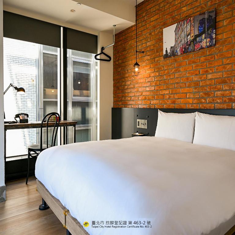 a bedroom with a white bed and a brick wall at CHECK inn Taipei Songjiang in Taipei
