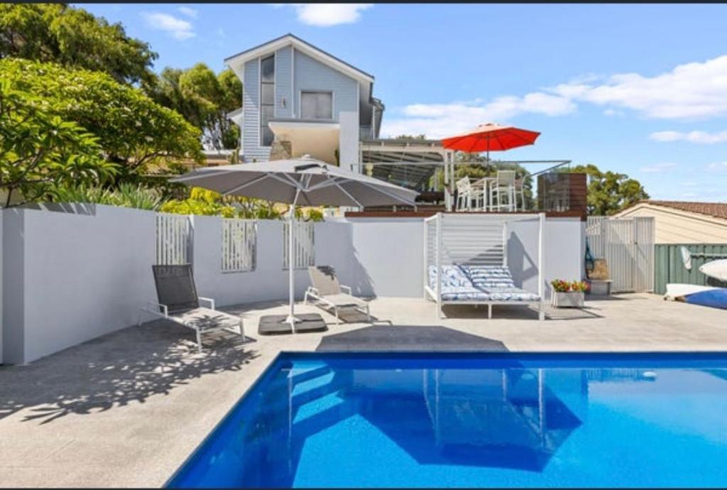 a swimming pool with two chairs and an umbrella at Quinns Oasis in Quinns Rocks