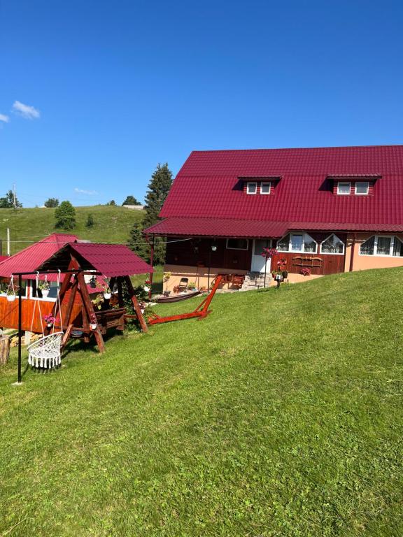 a building with a red roof and a playground at Cabana Daria in Gârda de Sus