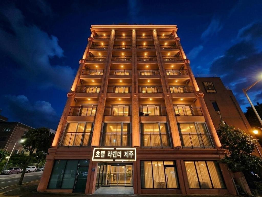 a tall building with a sign in front of it at Jeju Lavender Hotel in Seogwipo