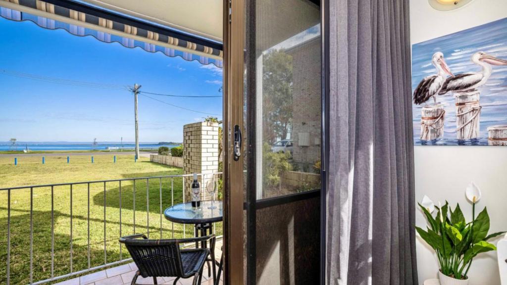 a door to a balcony with a view of the ocean at Great Views, Ground Floor Unit in Bongaree