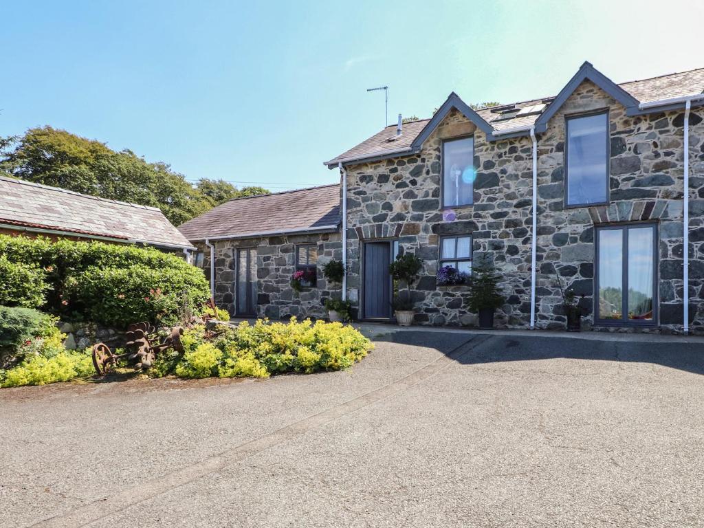 a stone house with a driveway in front of it at Wern Olau Cottage in Caernarfon