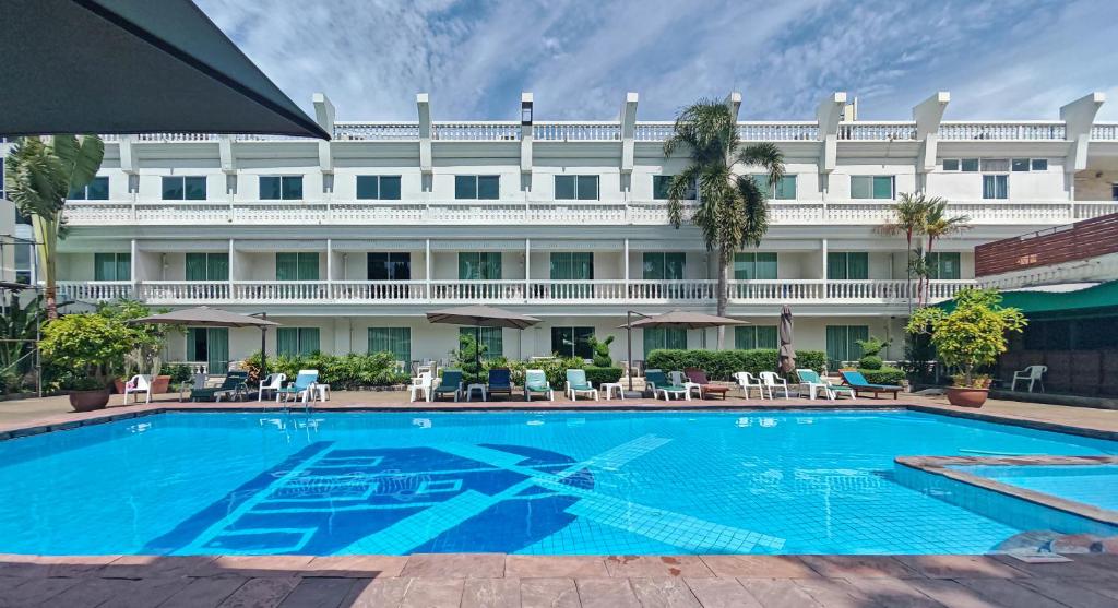 ein Pool vor einem großen weißen Gebäude in der Unterkunft Windmill Resort Hotel Pattaya in Pattaya North