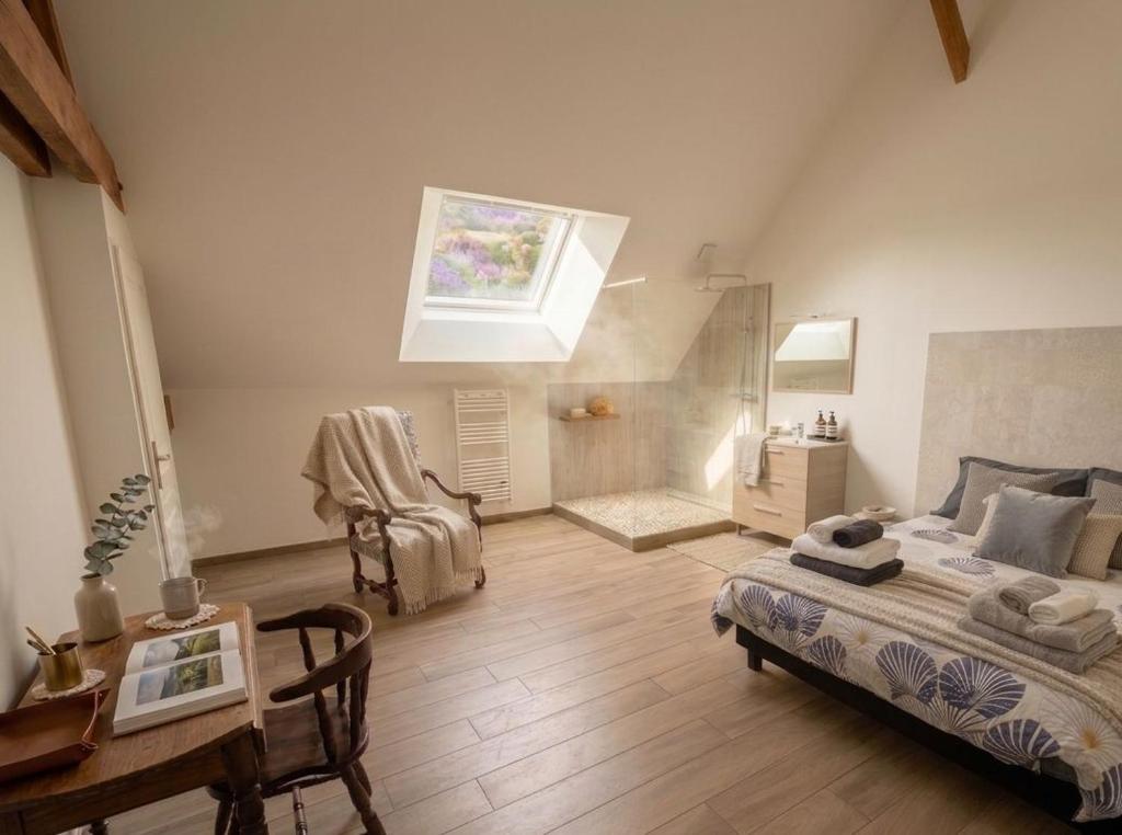 a bedroom with a bed and a table and a window at LE CHARME D OGNES in Ognes