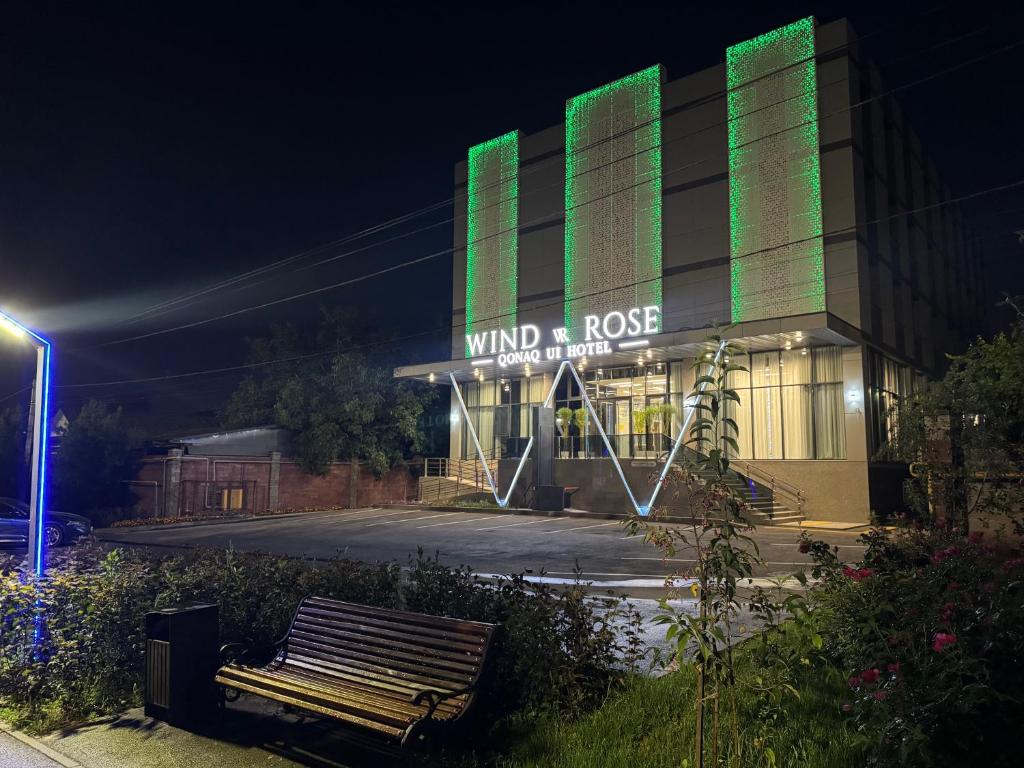 a building with a bench in front of it at night at Wind Rose in Almaty