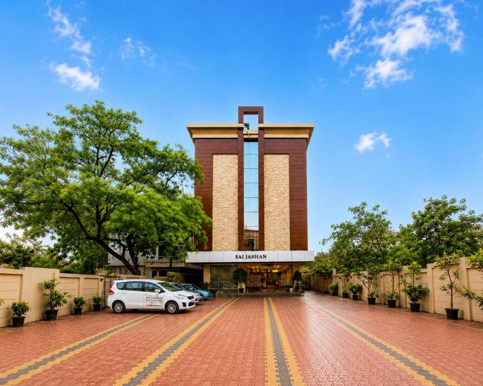 a building with a car parked in front of it at Hotel Sai Jashan Shirdi - Where blessings & comfort meet in Shirdi