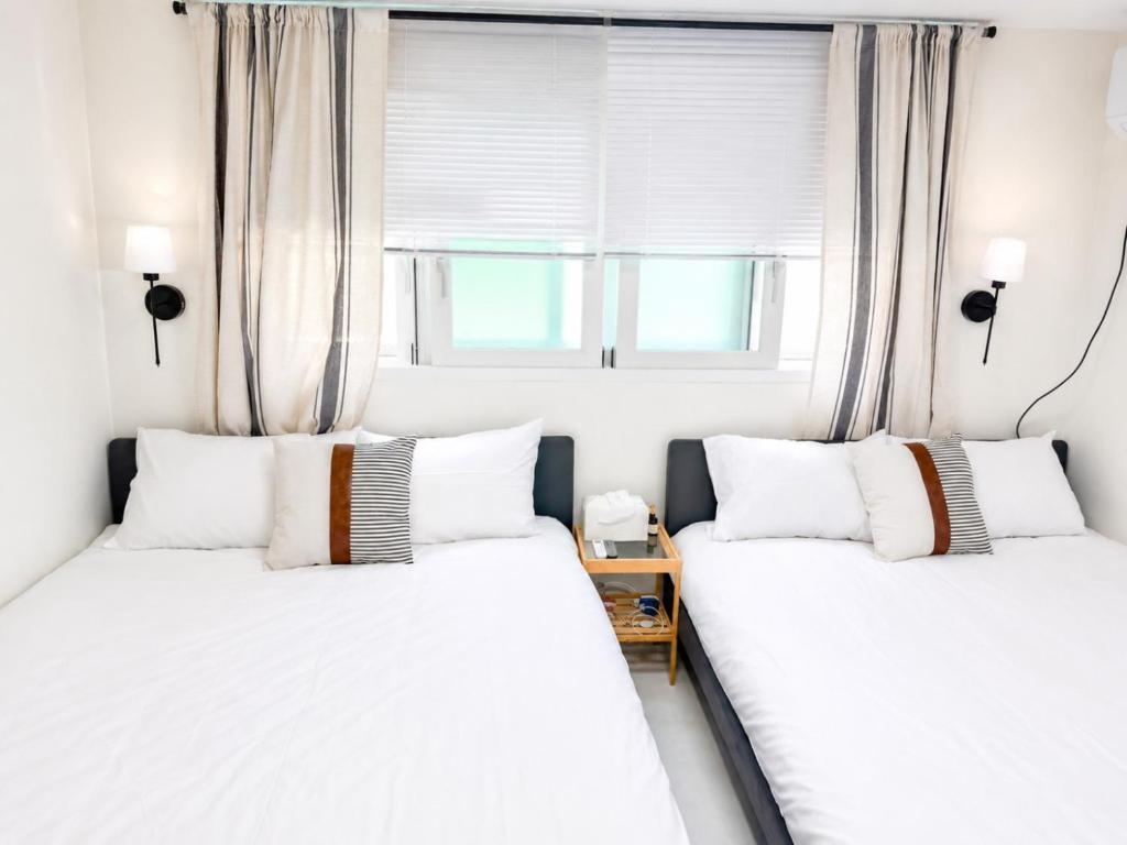 two twin beds in a room with a window at Woori Stay in Suwon