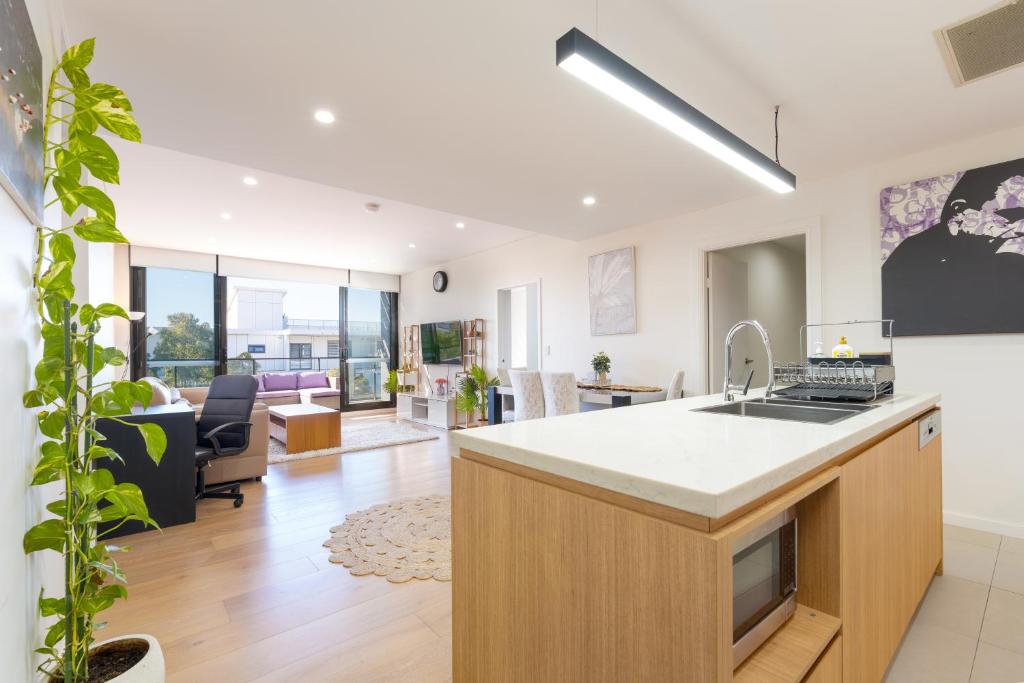 a kitchen with a sink and a living room at Rouse Hills TownCentre luxury accommodation in Kellyville