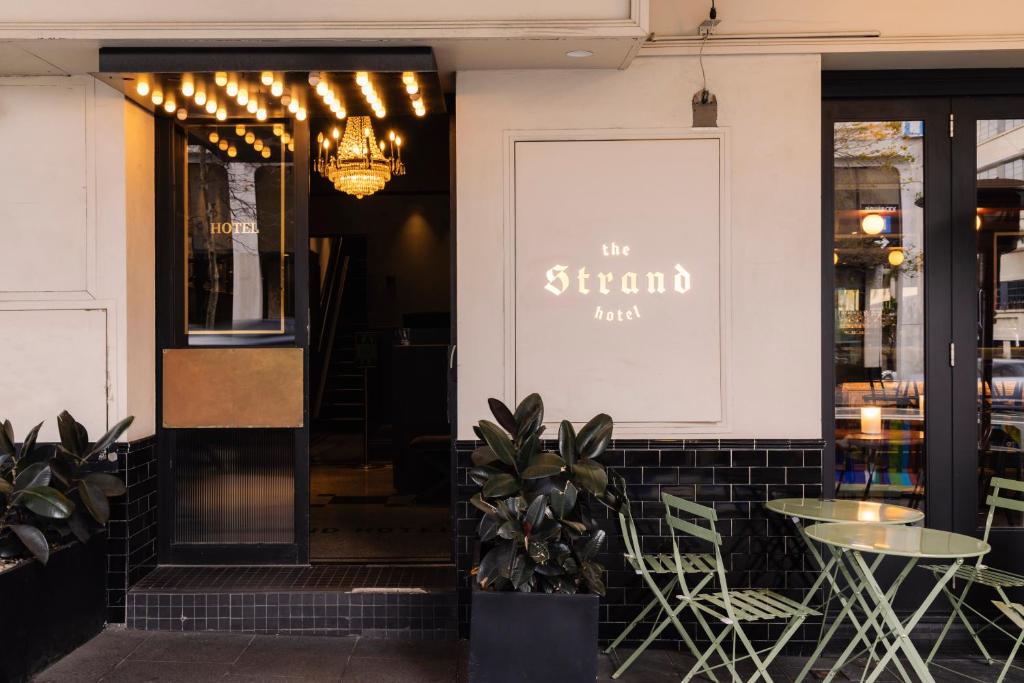 a restaurant with tables and chairs and a sign on the wall at The Strand Hotel in Sydney