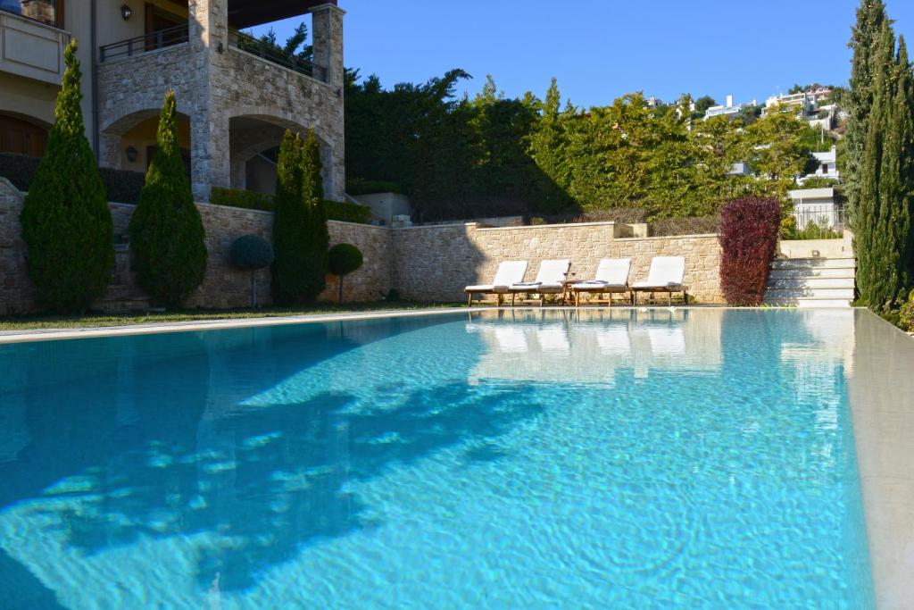 a swimming pool with two chairs and a building at Villa Marina, Sea View Luxury Villa in Mati