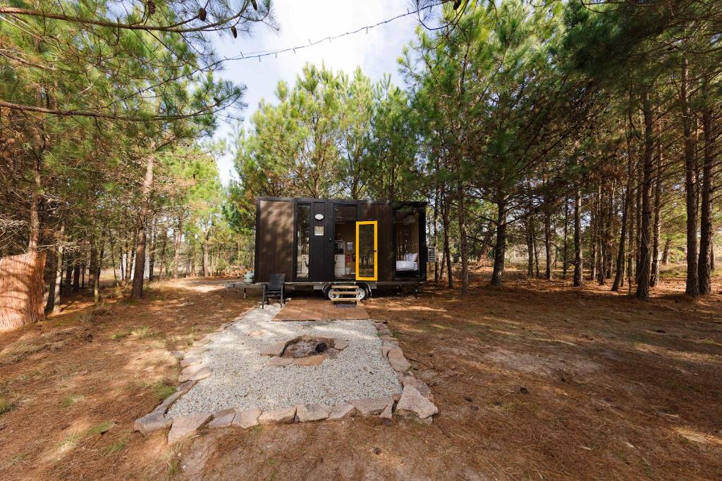 a black tiny house in the middle of a forest at The Hideaway at Novena Pines by Tiny Away in Thulimbah