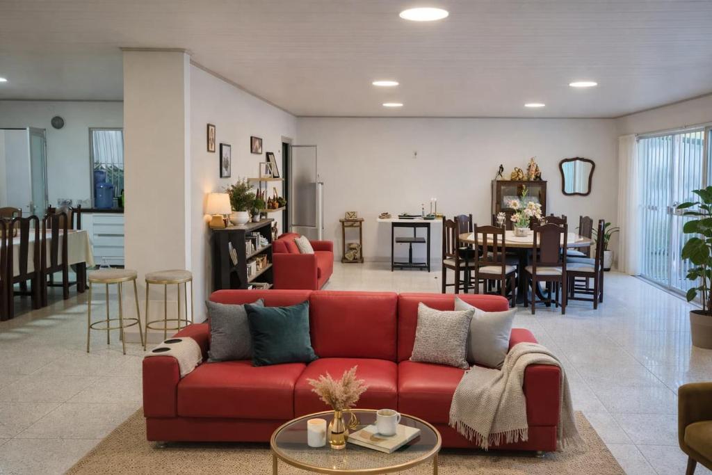 a living room with a red couch and a dining room at Quarto privativo em Guriri casa de praia in São Mateus