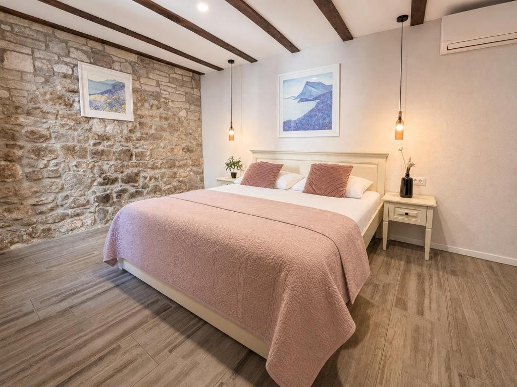 a bedroom with a bed and a stone wall at Split Old Town Rooms Matushko in Split