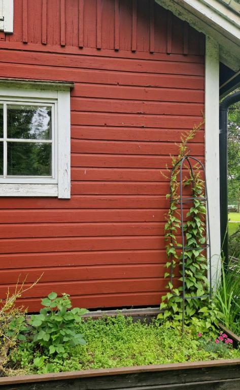 a red wall of a house with a window at Cute old garden cottage in Kirkkonummi