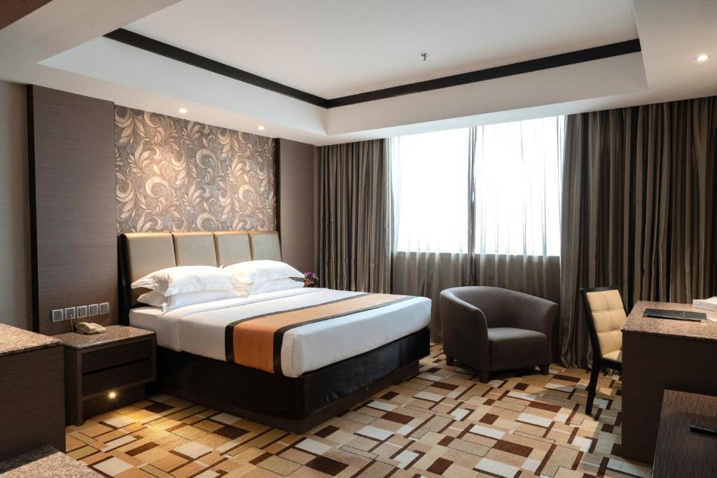 a hotel room with a bed and a chair at Grand Paragon Hotel Johor Bahru in Johor Bahru