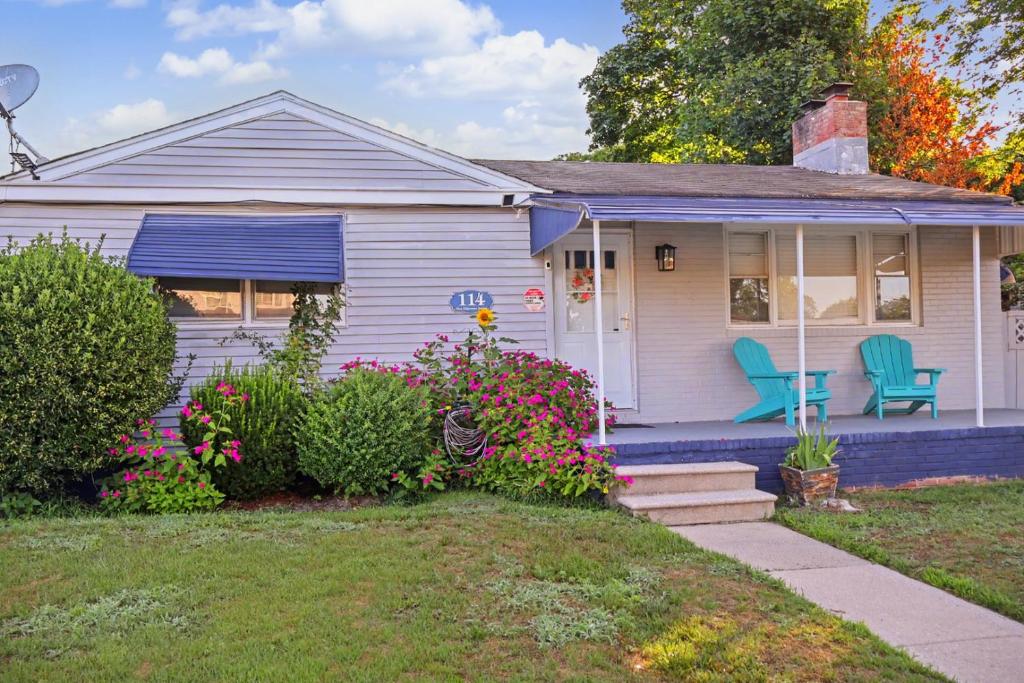 a white house with two blue chairs on the porch at Coastal Home at Edgewater in Pleasantville