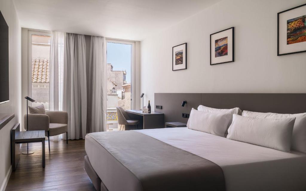 a hotel room with a large bed and a desk at Hotel Ogar Tomelloso in Tomelloso