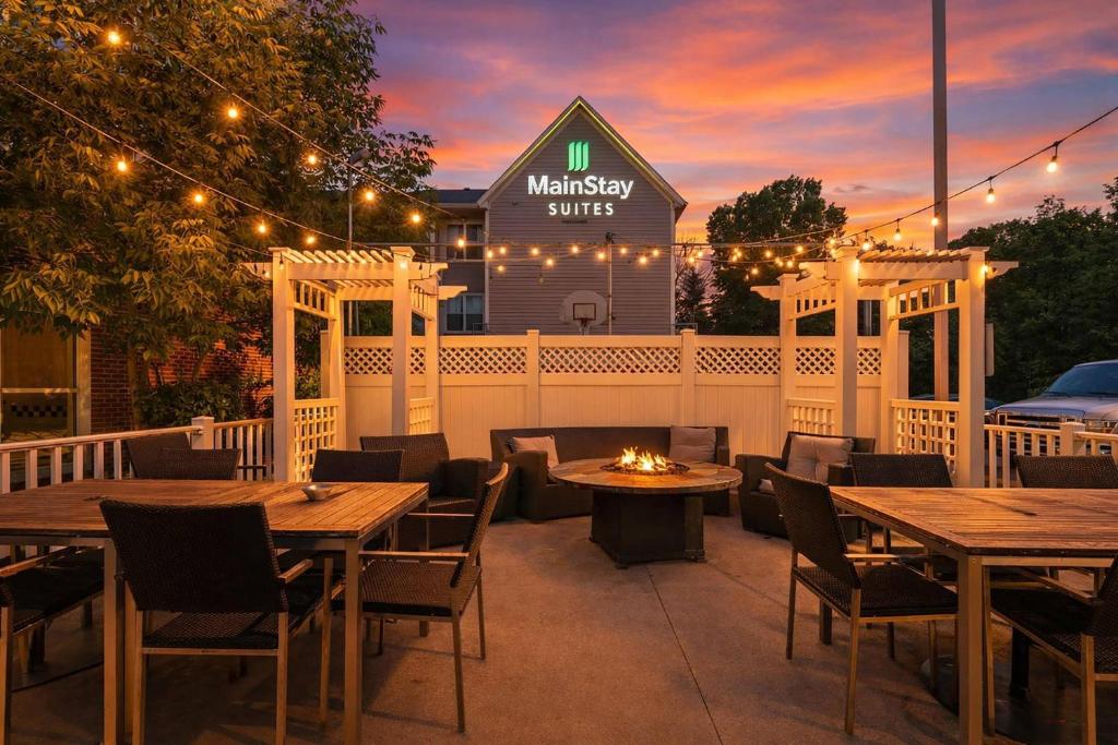 a patio with wooden tables and chairs and a restaurant at MainStay Suites Appleton Airport - Fox River Mall Area in Appleton