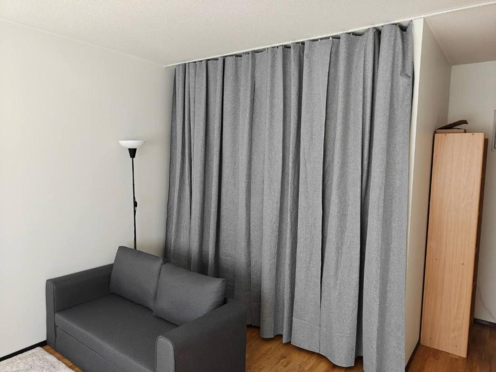 a living room with a couch and a curtain at Sunny 4th-Floor Park-View Studio Escape in Turku