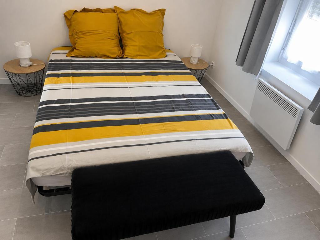 a large bed with yellow pillows and a window at violette 3 in La Souterraine