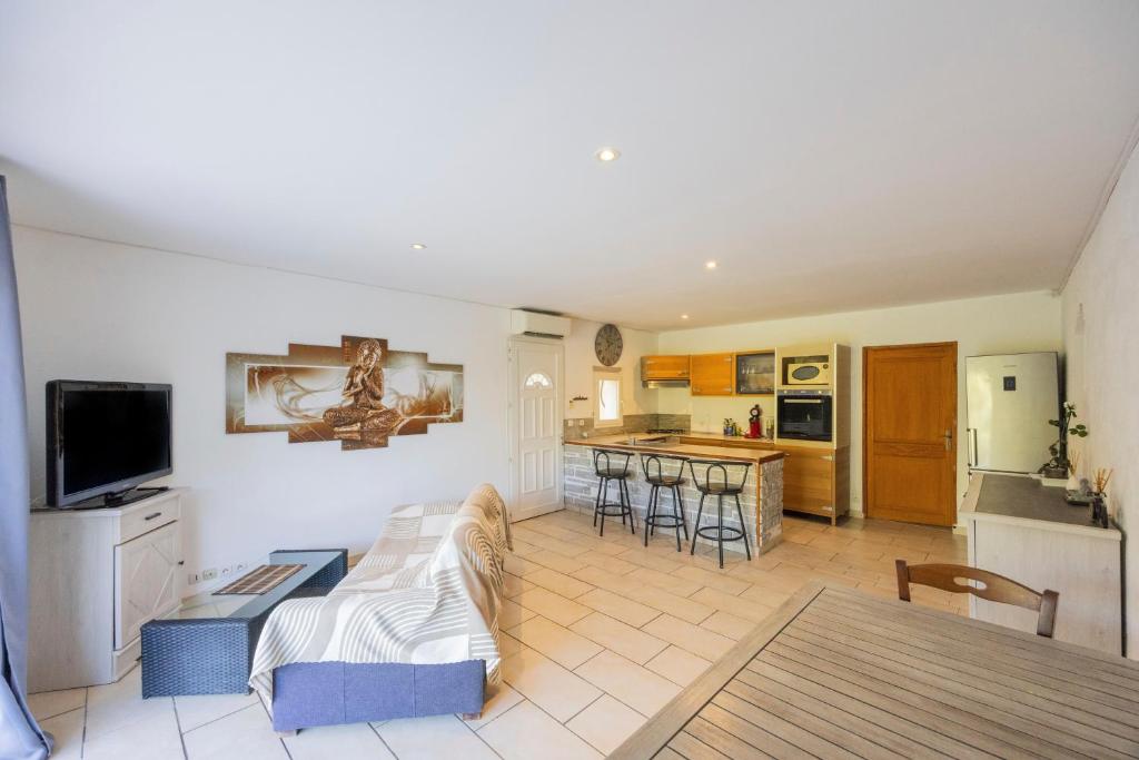 a living room with a couch and a kitchen at Appartement Aléria avec jardin in Aléria