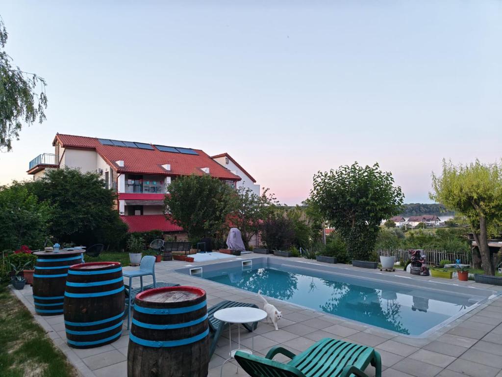 a swimming pool with chairs and a table and a house at Pensiunea 4 Salcii in Băltenii de Sus