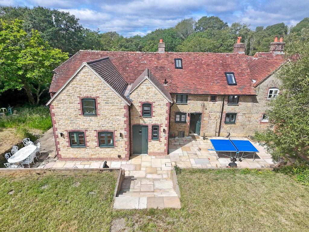 an old brick house with a tennis court in the yard at Swallows Bottom in Henley