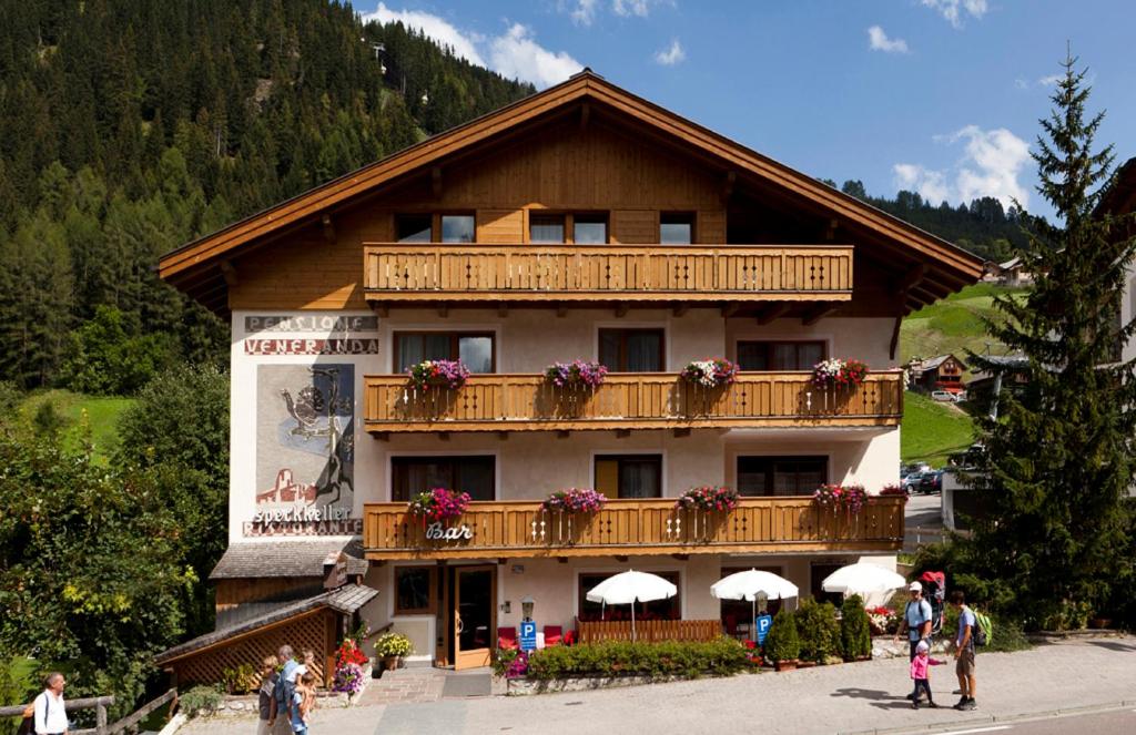 a building with a balcony with flowers on it at Hotel Pensione Veneranda in Corvara in Badia