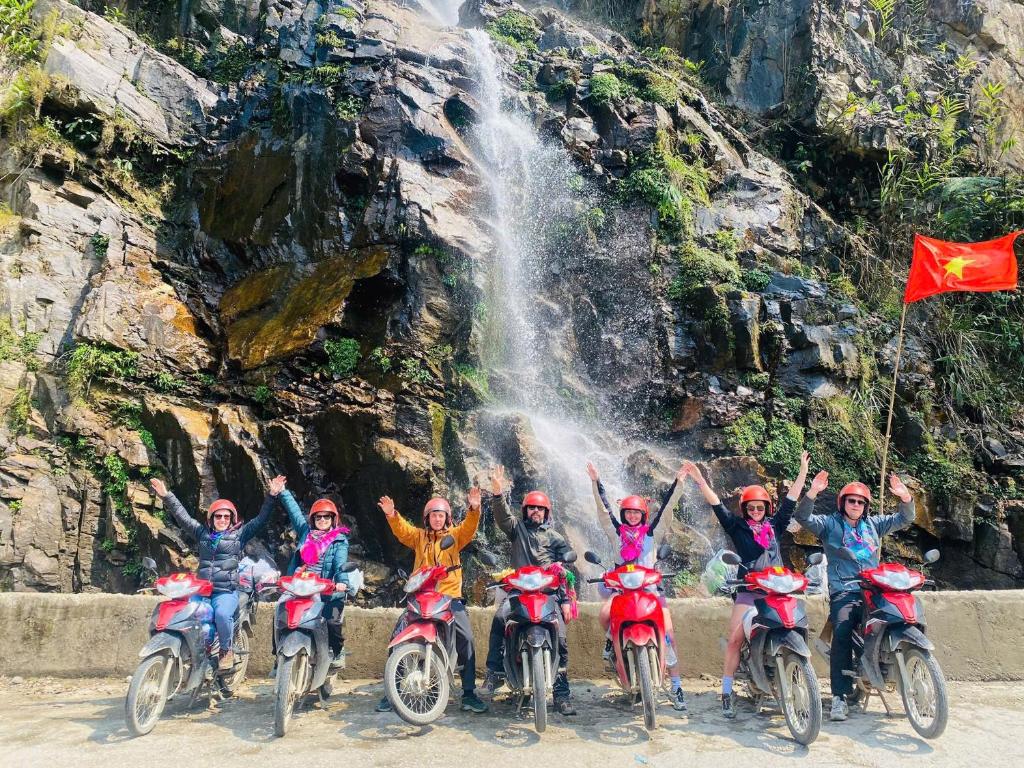 a group of people on motorcycles in front of a waterfall at Downtown Hostel HANOI & HA GIANG LOOP TOUR OFFICE in Hanoi