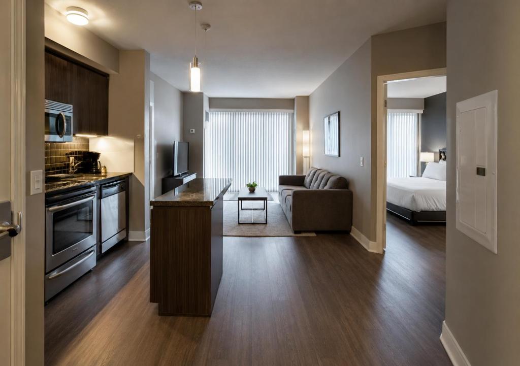 a room with a kitchen and a living room with a couch at Oak Crown Suites in Toronto