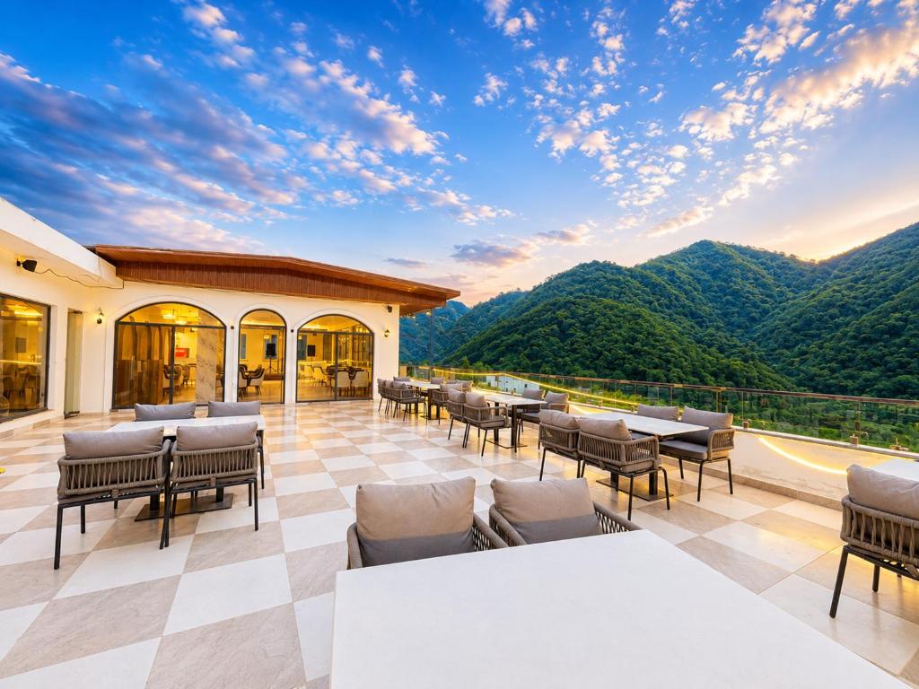 a patio with tables and chairs and a view of mountains at Hotel Weekend Heights in Rishīkesh