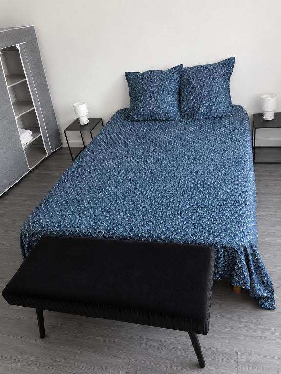 a bedroom with a bed with a blue comforter at Violette 2 in La Souterraine